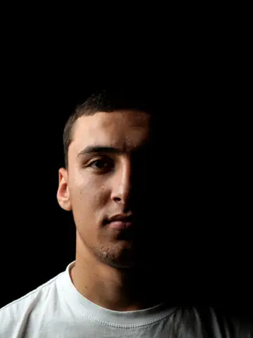 A footballer photographed in dramatic low light