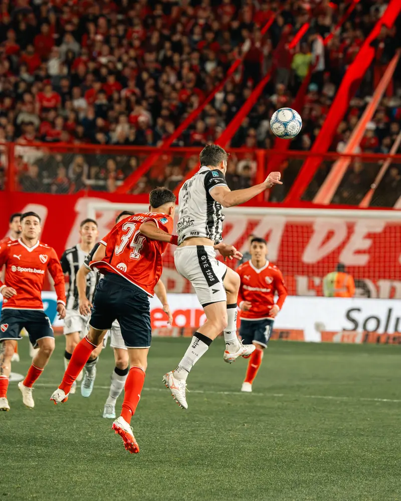 Players challenging for a header in front of a packed stadium